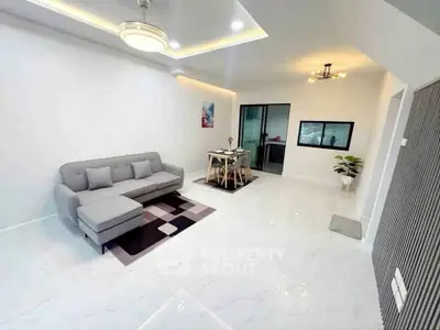 Modern living room with sleek design and open layout, featuring a cozy gray sofa and stylish dining area.