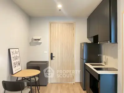 Modern compact kitchen with sleek black cabinets and dining area