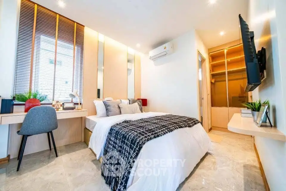 Modern bedroom with stylish decor and natural light, featuring a cozy bed and workspace.