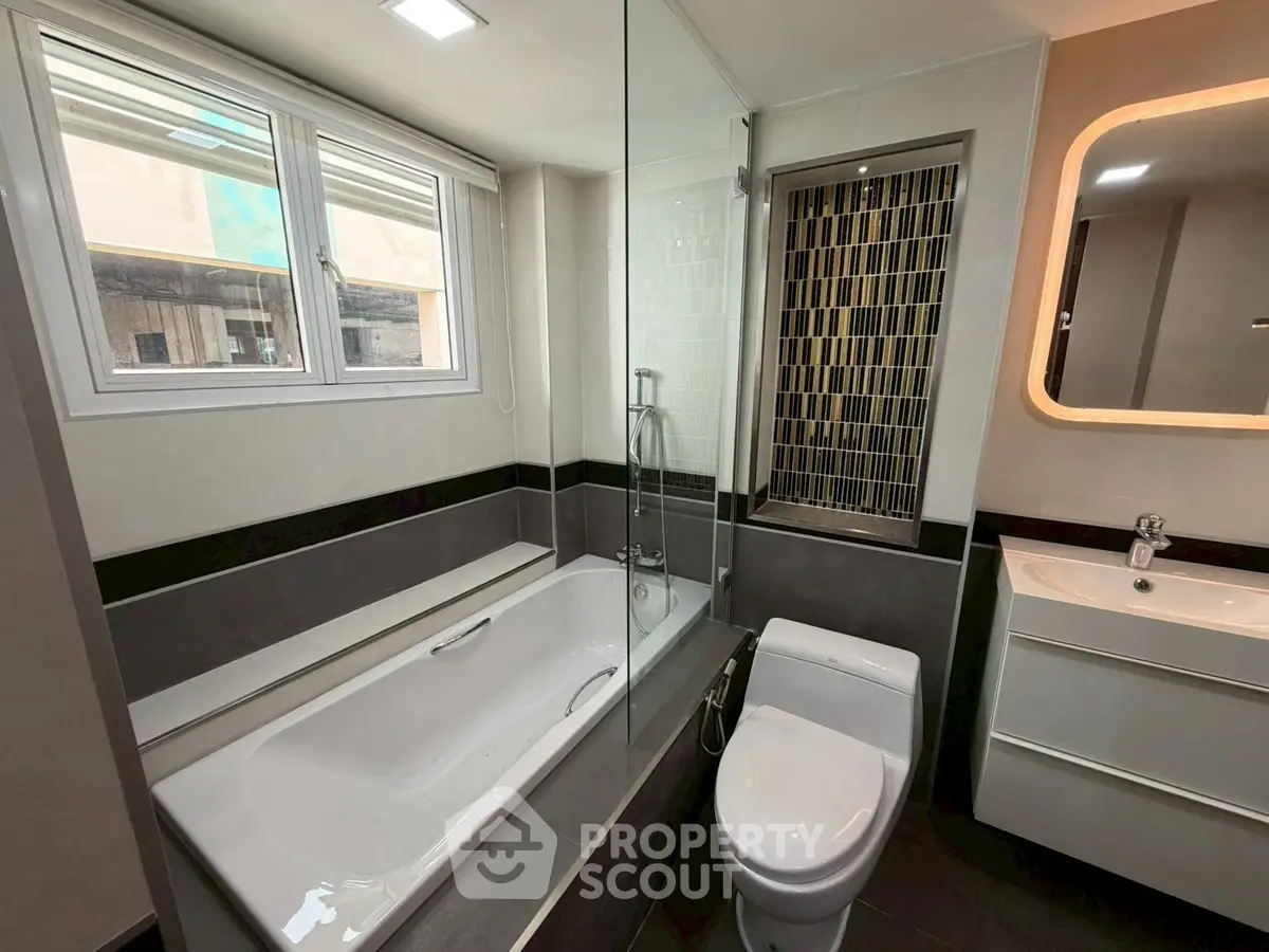 Modern bathroom with sleek design, featuring a bathtub and stylish fixtures.
