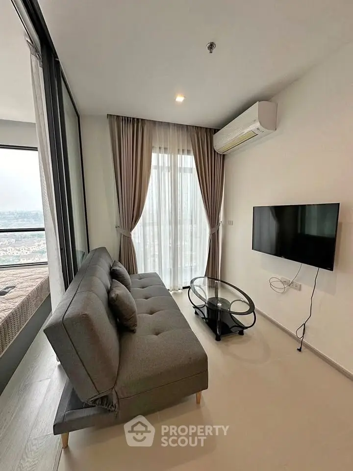 Modern living room with sleek sofa, wall-mounted TV, and large window with city view.