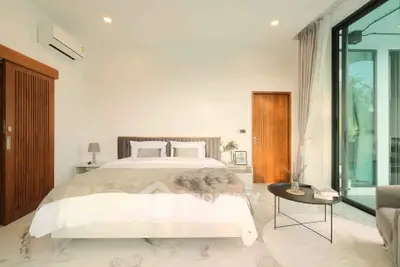 Luxurious bedroom with modern decor and large glass doors opening to a serene view.