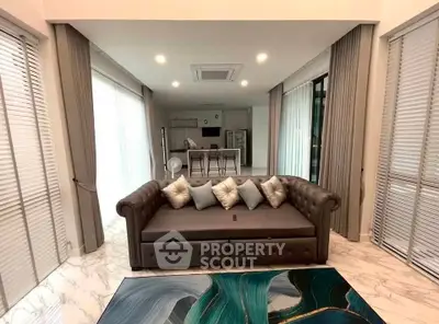 Luxurious modern living room with elegant sofa and open kitchen layout, featuring marble flooring and stylish decor.