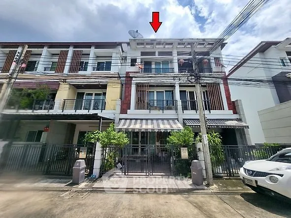 Modern townhouse with three floors and gated entrance in a residential area.