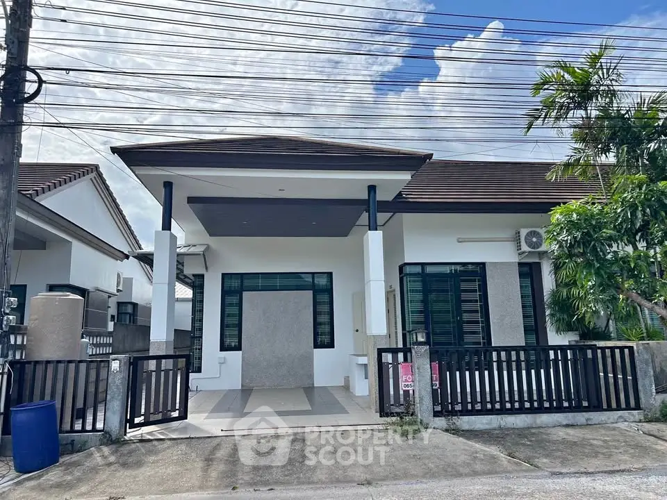 Charming single-story house with modern facade and gated entrance in a serene neighborhood.