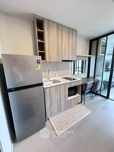 Modern kitchen with sleek cabinetry, integrated appliances, and a compact dining area in a stylish apartment.