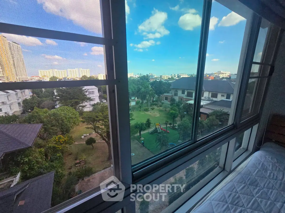 Stunning cityscape view from a modern apartment window, showcasing lush greenery and urban skyline.