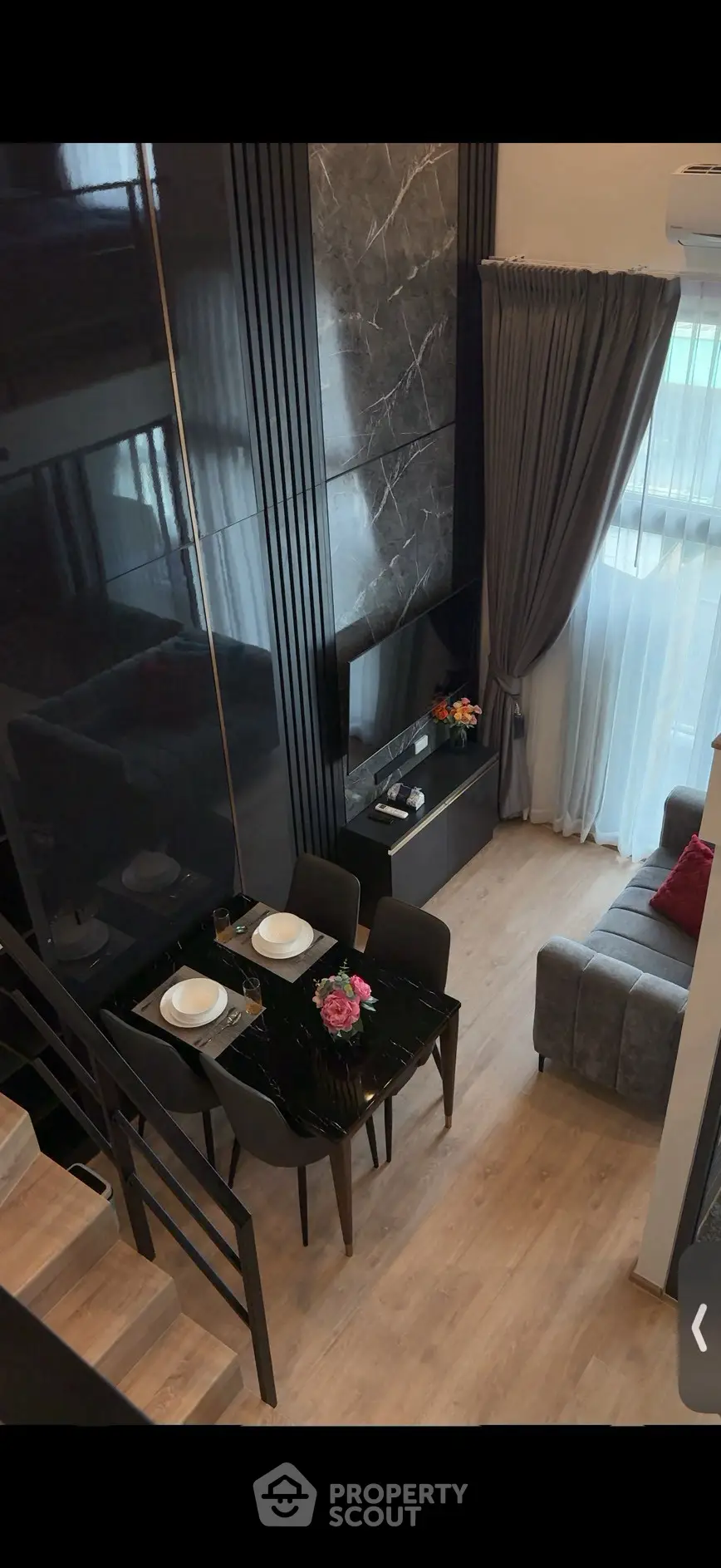 Modern duplex living room with elegant decor and dining area, featuring sleek black accents and large windows.
