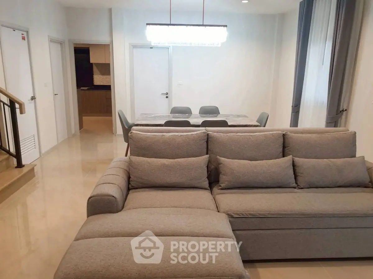 Spacious living room with modern gray sofa and dining area in open layout