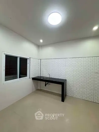 Modern minimalist kitchen with sleek black countertop and white subway tile backsplash.