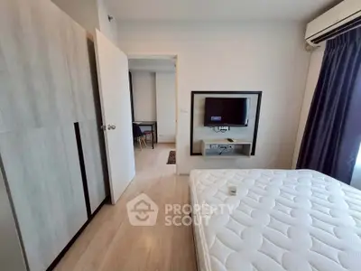 Modern bedroom with minimalist design, featuring a wall-mounted TV and ample natural light.