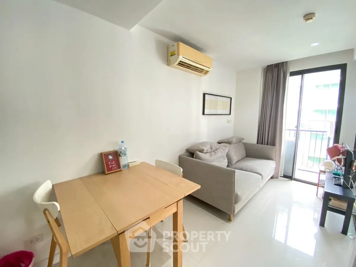 Modern living room with cozy sofa, dining table, and balcony access in a bright apartment.