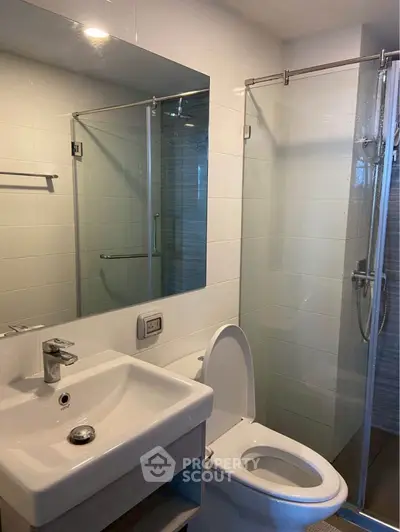 Modern bathroom with glass shower and sleek fixtures in a contemporary apartment.