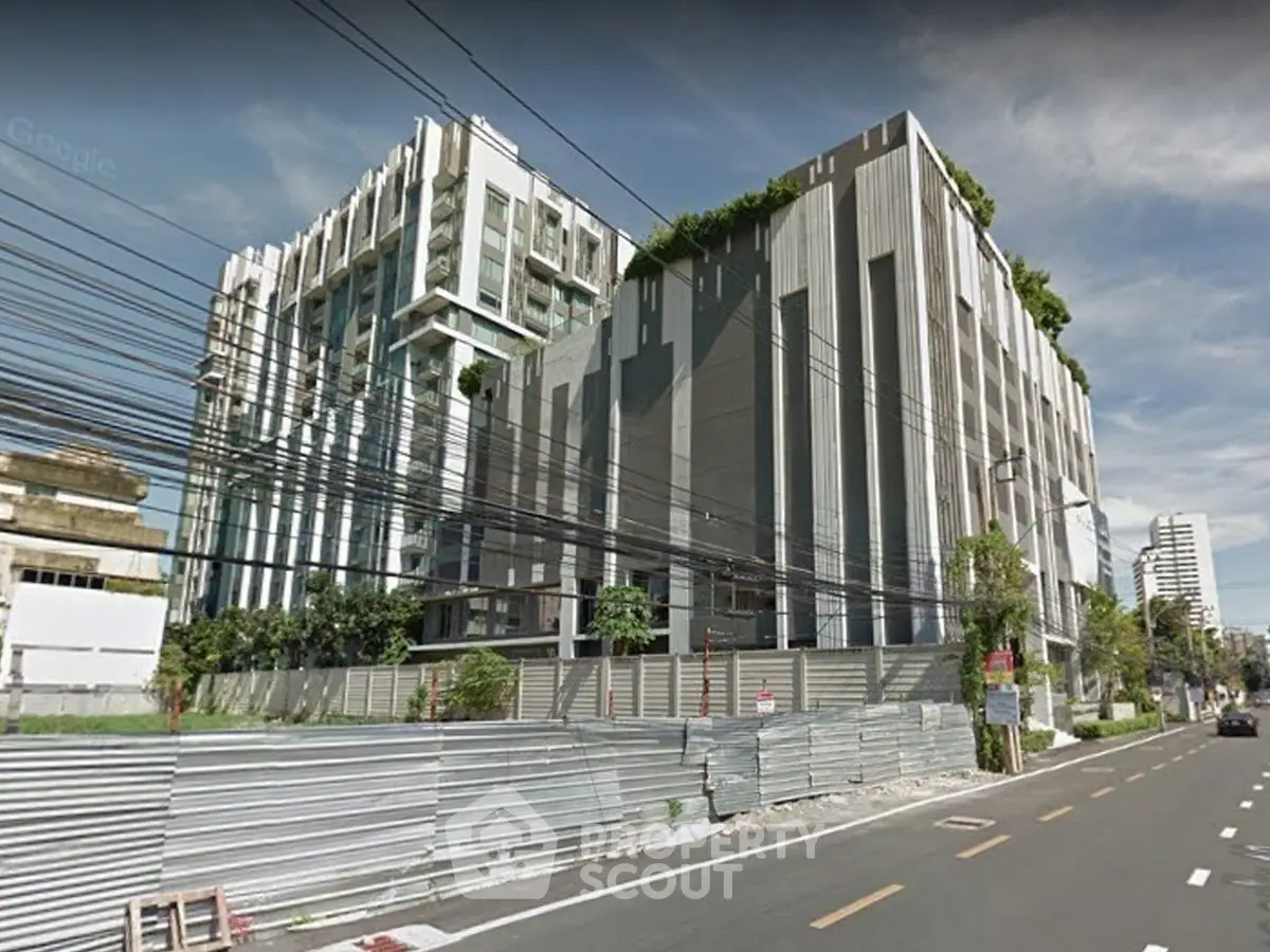 Modern urban building exterior with lush greenery and sleek design on a sunny day.