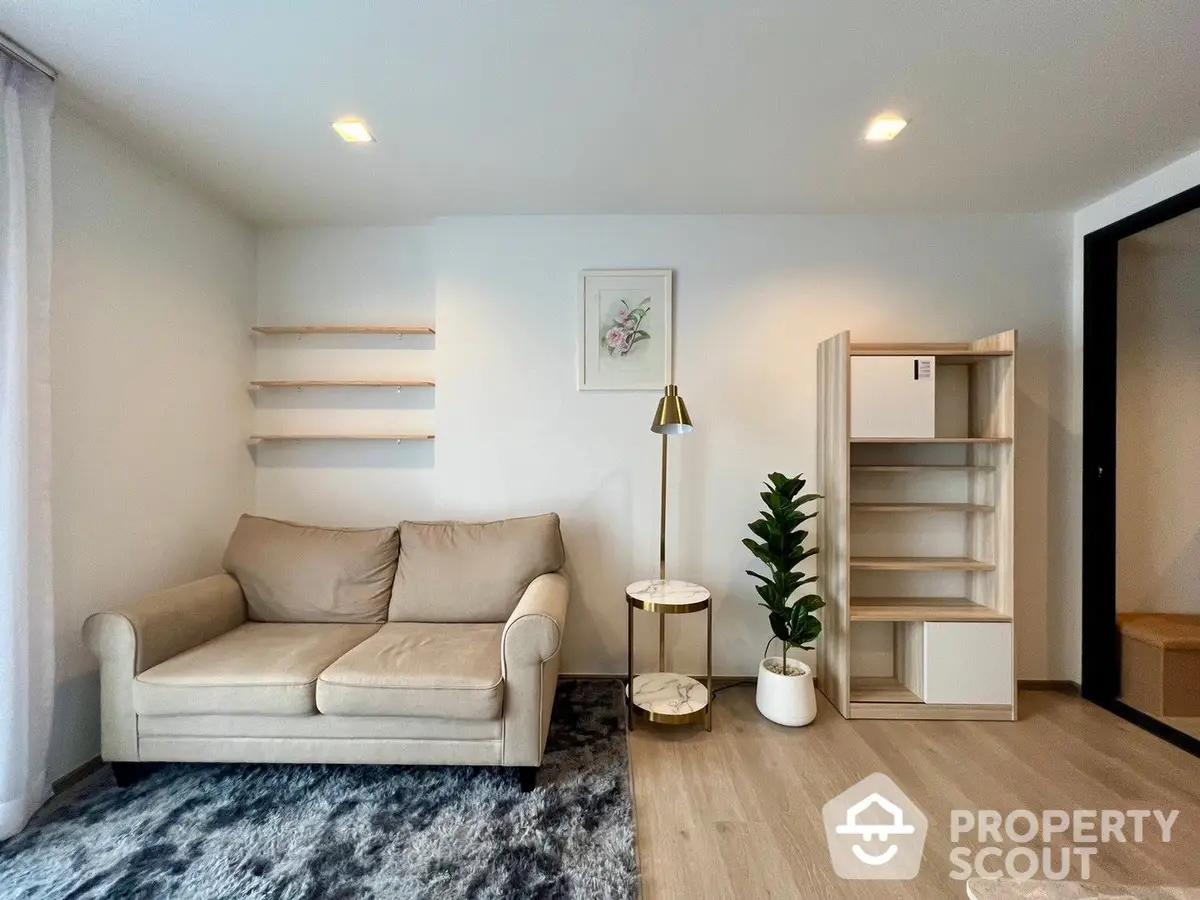 Modern minimalist living room with elegant beige sofa, chic gold-accented side table, and a lush potted plant enhancing the cozy ambiance.