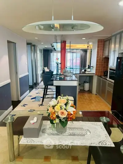 Spacious open-plan living and kitchen area with modern decor and floral centerpiece.