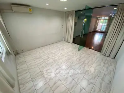 Spacious tiled room with glass partition and air conditioning, ideal for versatile living space.