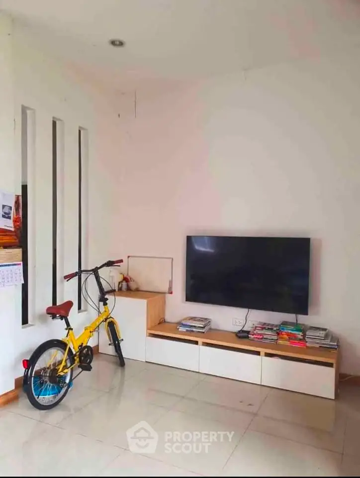 Modern living room with sleek TV setup and vibrant yellow bicycle for a stylish urban lifestyle.