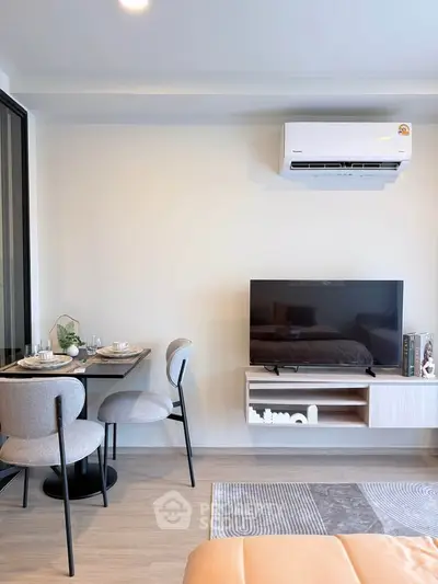 Modern living room with dining area and wall-mounted TV in stylish apartment.
