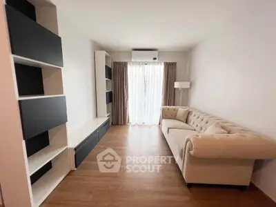 Modern living room with elegant sofa and built-in shelves, featuring natural light and wooden flooring.