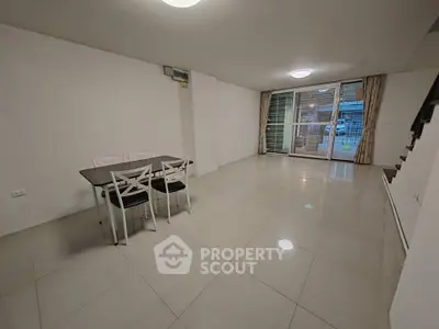 Spacious dining area with modern table and chairs, large windows, and sleek tile flooring.