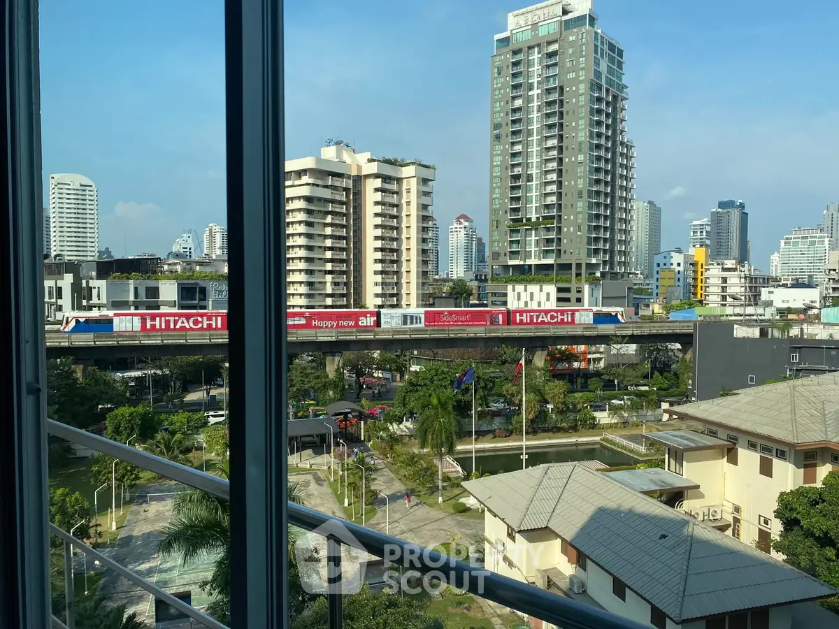 Stunning city view from high-rise apartment window with skyline and train track.