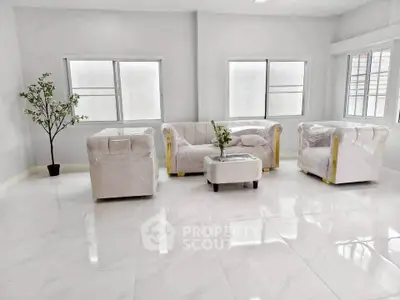Spacious modern living room with elegant white furniture and large windows.