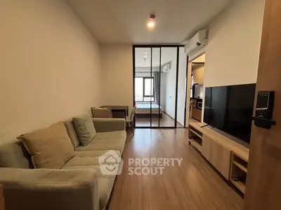 Modern apartment interior with cozy living room and open view to bedroom, featuring sleek wooden flooring.