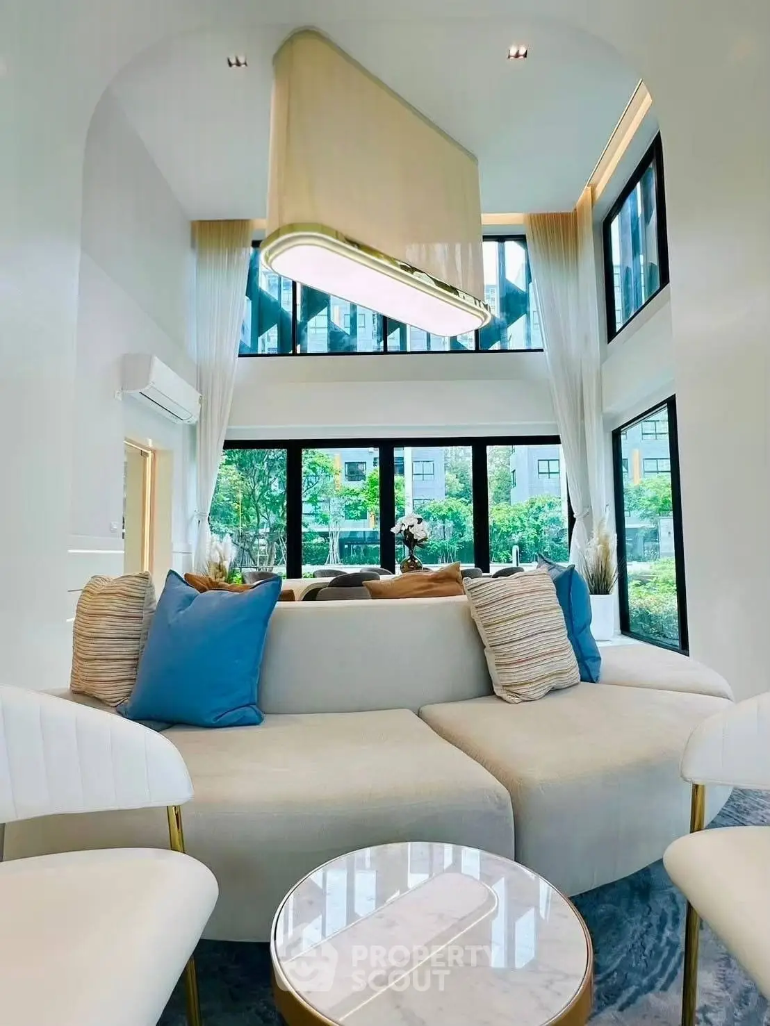 Luxurious modern living room with high ceilings and large windows offering a stunning view.