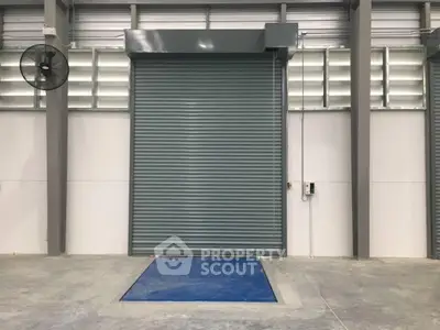 Industrial warehouse with large roller shutter door and concrete flooring
