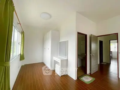 Spacious bedroom with wooden flooring and ample natural light