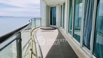 Luxurious curved balcony with stunning ocean view and glass railing.