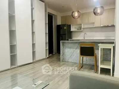 Modern kitchen with sleek cabinetry and marble island in open layout apartment.