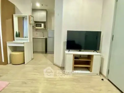 Modern living room with TV and compact kitchen in open layout apartment