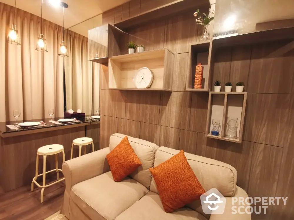 Cozy living room with modern decor, featuring a beige sofa, stylish shelving, and a breakfast bar with stools.