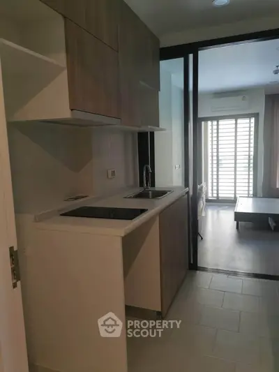 Modern compact kitchen with sleek cabinetry and sliding glass doors leading to a bright living area.