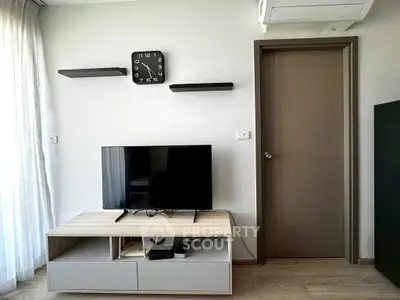Modern living room with sleek TV stand and wall-mounted shelves, featuring a minimalist clock and air conditioning.