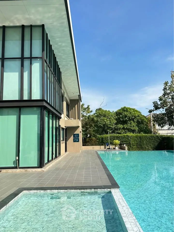 Luxurious modern building with a stunning outdoor pool and lush greenery, perfect for relaxation and leisure.