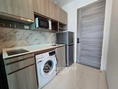 Modern compact kitchen with washing machine and microwave in stylish apartment