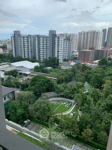 Stunning cityscape view from a high-rise apartment overlooking lush greenery and modern buildings.