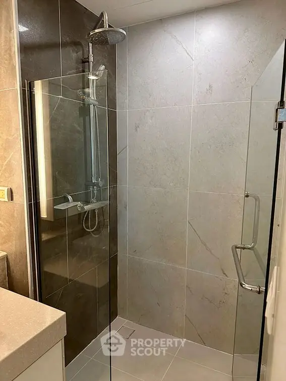 Modern bathroom with glass shower enclosure and sleek tile design.