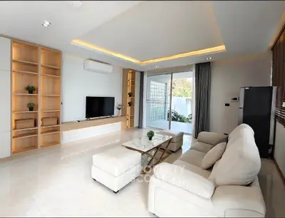 Spacious modern living room with elegant furniture and large windows opening to a balcony.