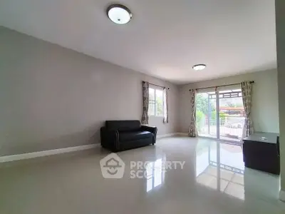 Spacious living room with large windows and sleek black sofa, offering abundant natural light and modern design.