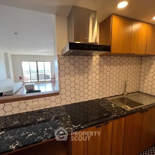 Modern kitchen with hexagonal tile backsplash and open layout to living room.
