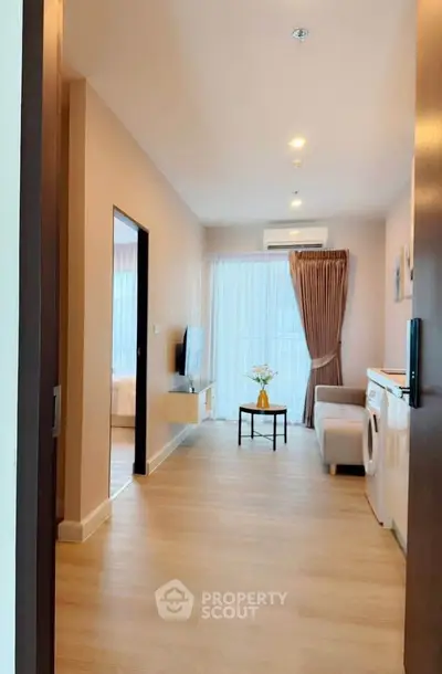 Modern living room with washing machine and cozy seating area, featuring natural light and elegant decor.