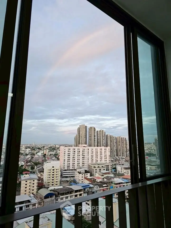 Stunning cityscape view from a high-rise balcony with a rainbow in the sky.