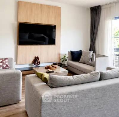 Modern living room with stylish furniture and wall-mounted TV, featuring natural light and elegant decor.
