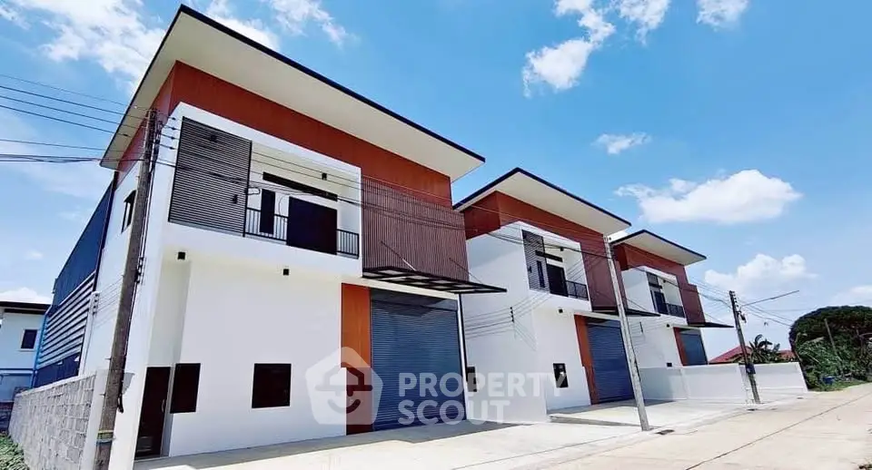 Modern townhouse exterior with sleek design and spacious balconies under clear blue sky.