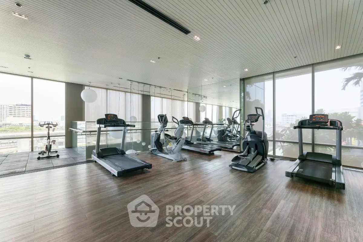 Modern gym with state-of-the-art equipment and large windows offering city views.