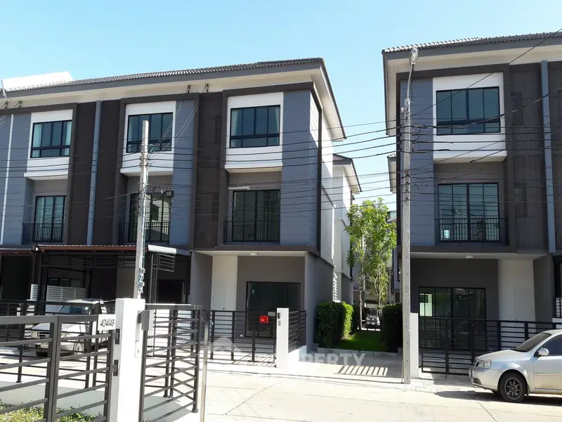 Modern townhouse exterior with sleek design and large windows in a suburban neighborhood.